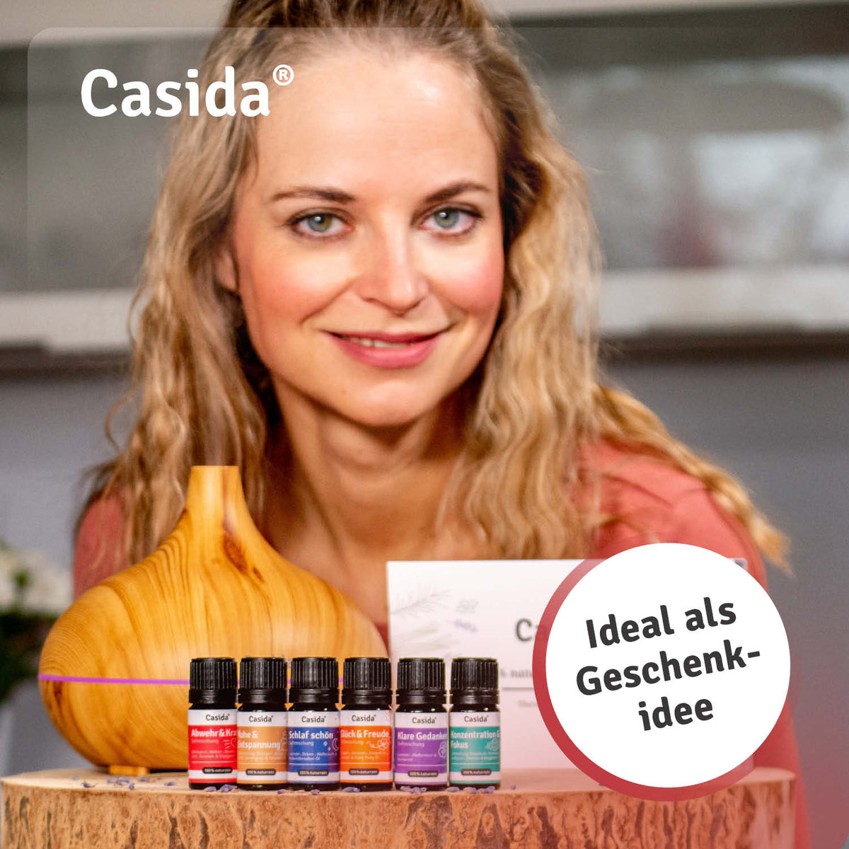 Aroma diffuser in wood design with six essential oil blends displayed in front of a woman.