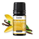 Bio Vanille Extrakt by Casida in a black bottle with yellow label, surrounded by vanilla pods and flowers.