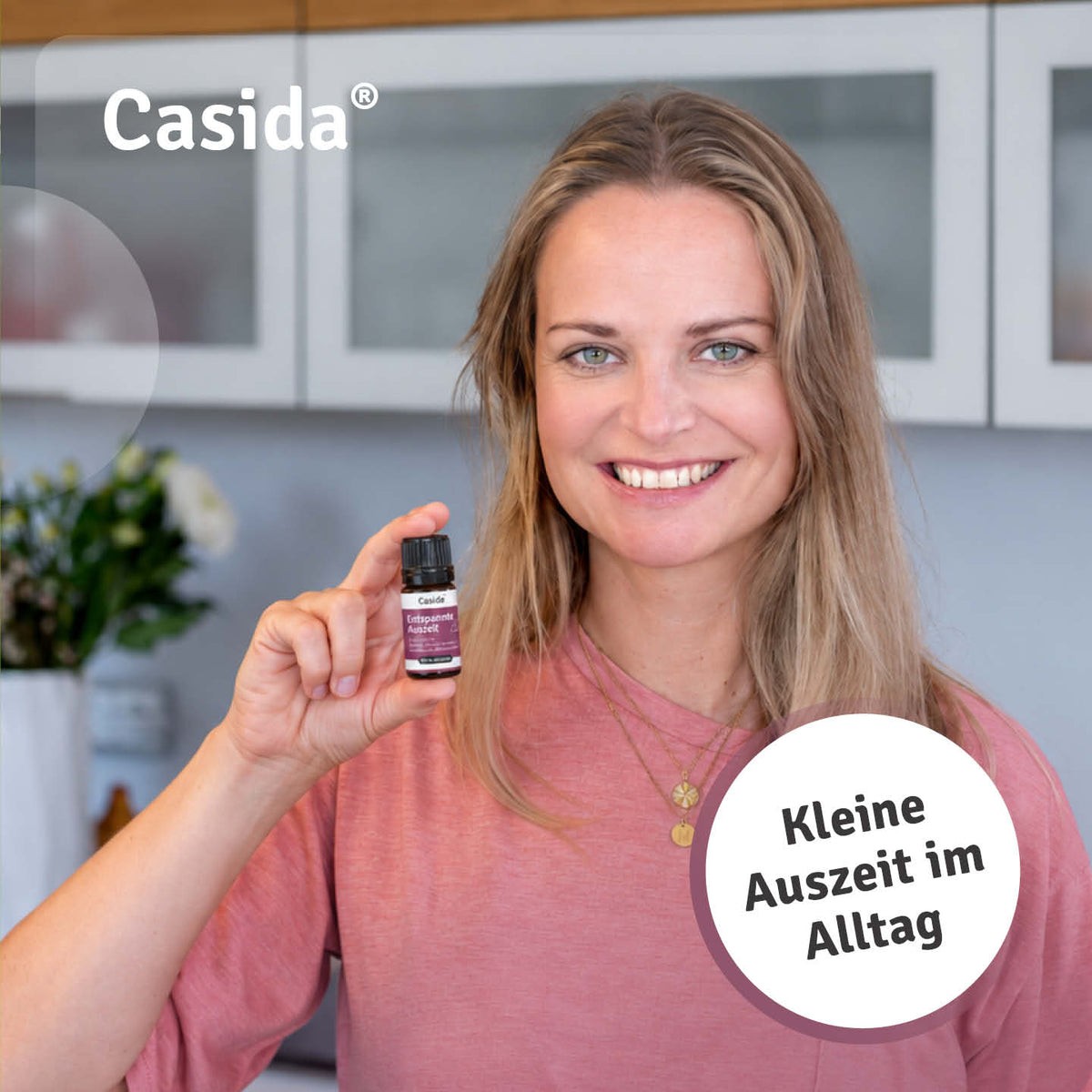 Lächelnde Frau im rosa Oberteil hält eine Flasche Casida Entspannte Auszeit in die Kamera