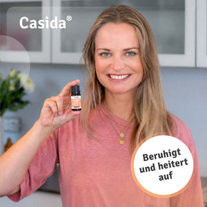 Lächelnde Frau im rosa Oberteil hält eine Flasche Casida Sorgenpause in die Kamera