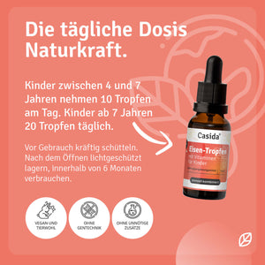 Eisen Tropfen mit Vitaminen für Kinder in brauner Flasche, Pipette oben, auf rosa Hintergrund mit Dosierungsanleitung.