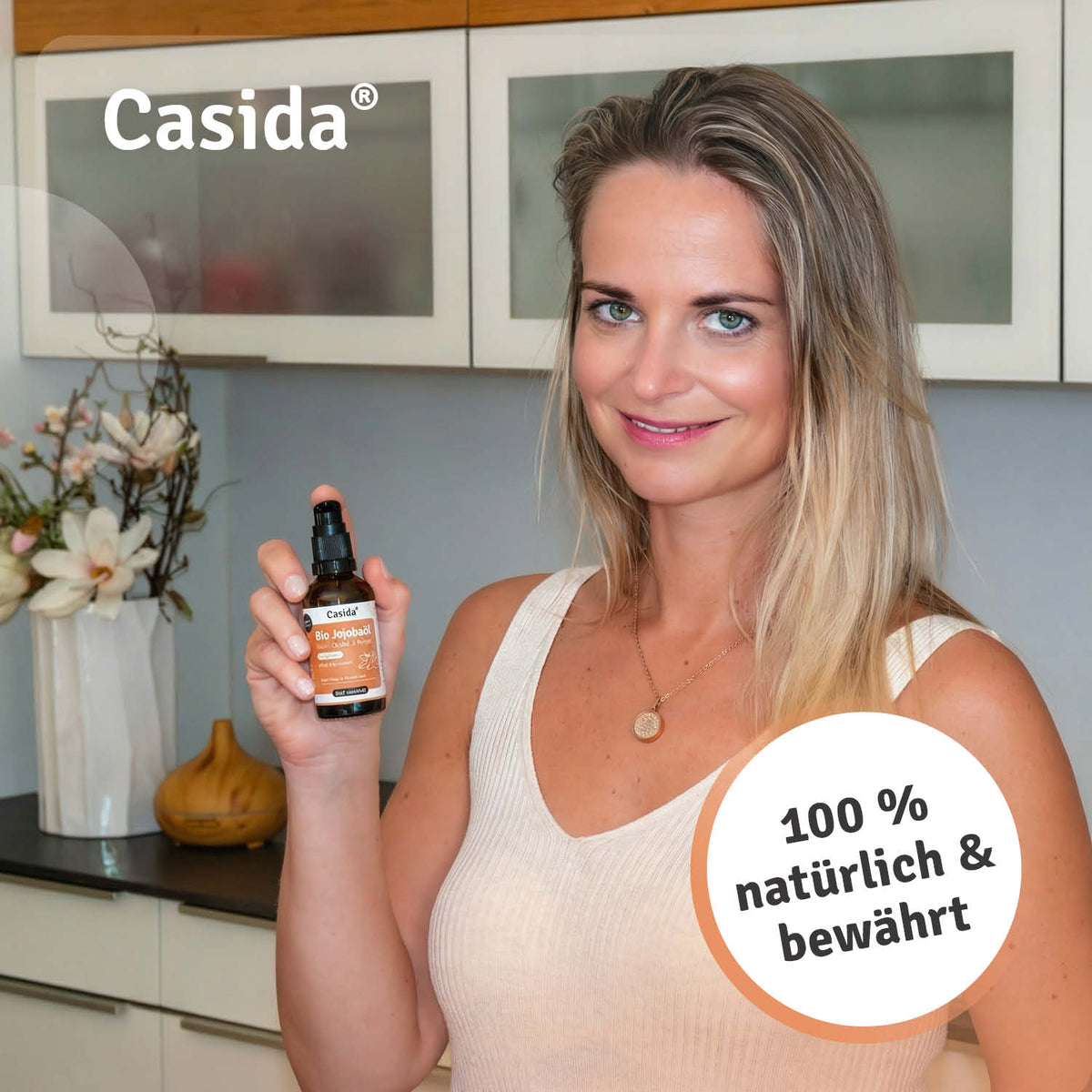 Casida jojoba oil bottle held by a woman in a kitchen, featuring a natural and organic label.