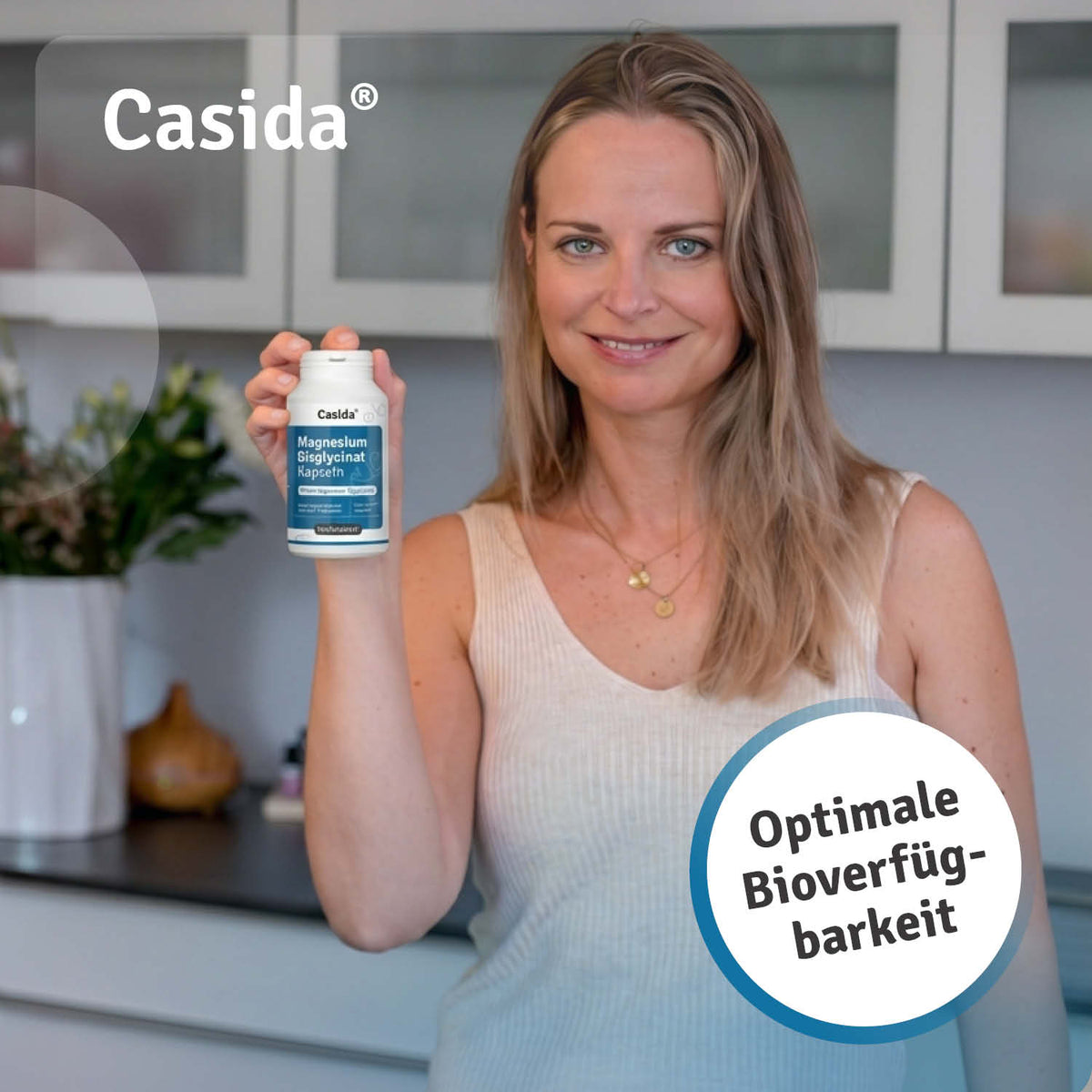 Casida bisglycinate magnesium capsules held by a woman in a kitchen, featuring a blue label and white bottle.
