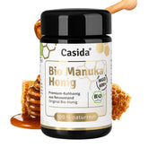 Casida Bio Manuka Honig MGO 600+ in a black jar with a honey dipper and honeycomb background.