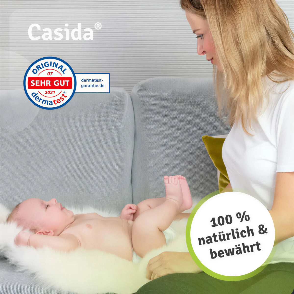 Engelwurzbalsam Baby & Kinder displayed with a mother and baby on a couch, featuring a soft white blanket and green pillow.