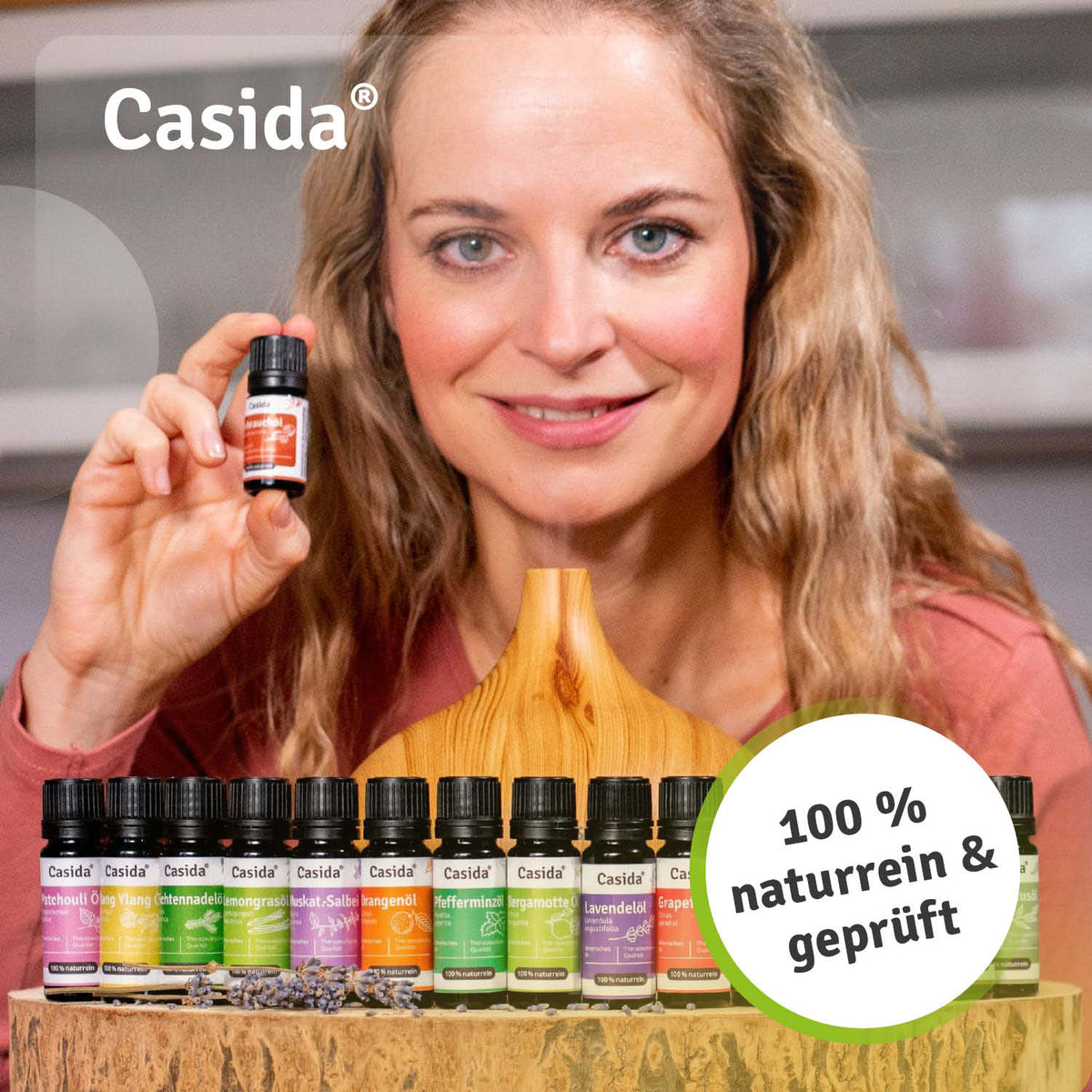 Top 16 ätherische Öle set displayed on a wooden stand, featuring various colored bottles and a woman holding one bottle.