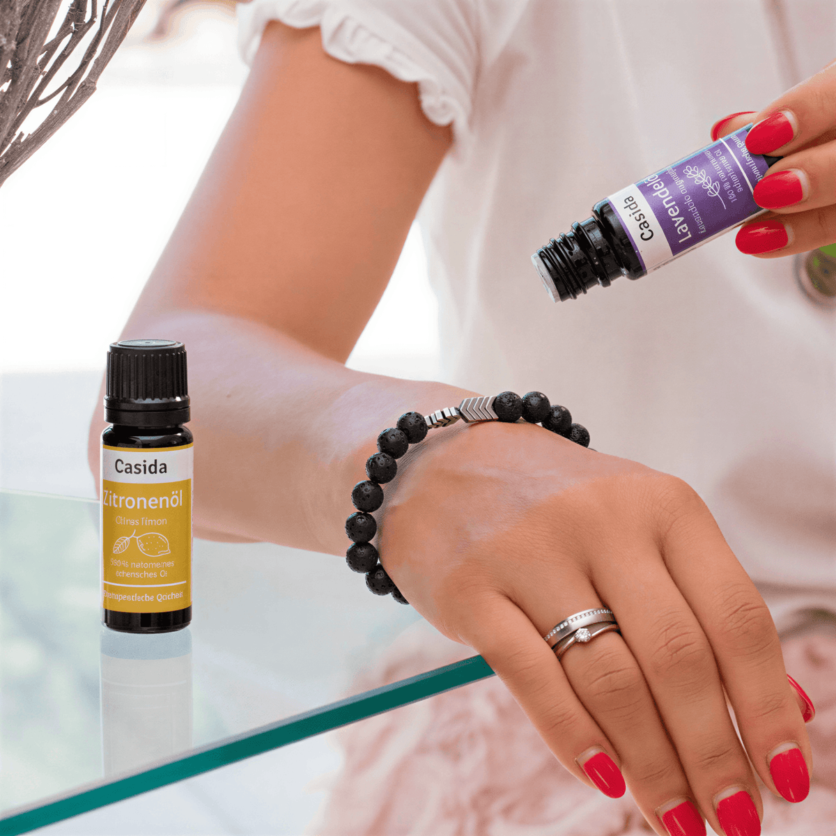 Chakra bead bracelet with 8 mm natural stone beads, worn on a wrist, alongside essential oil bottles.