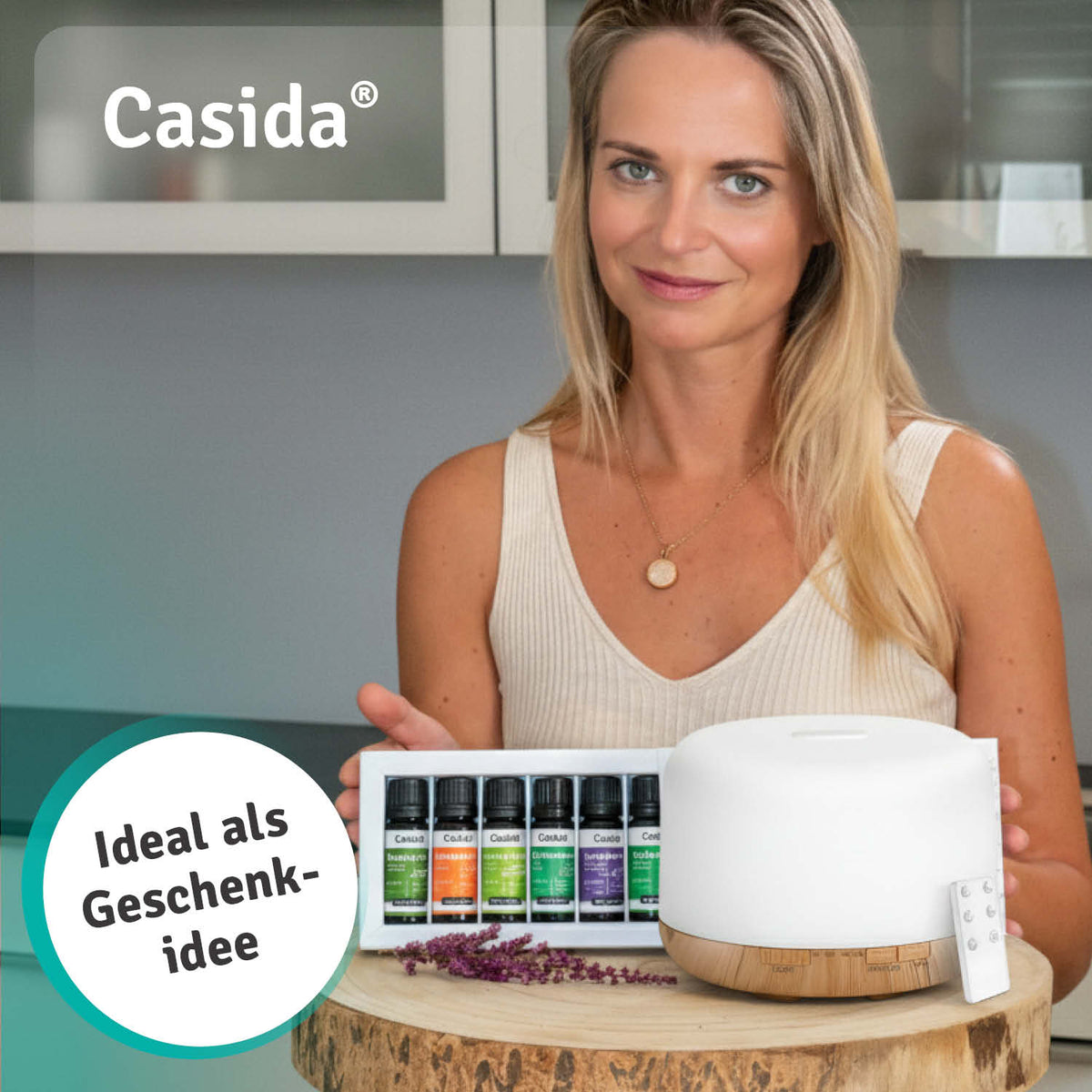 Aroma diffuser in white with remote control and six essential oils displayed on a table, held by a woman.