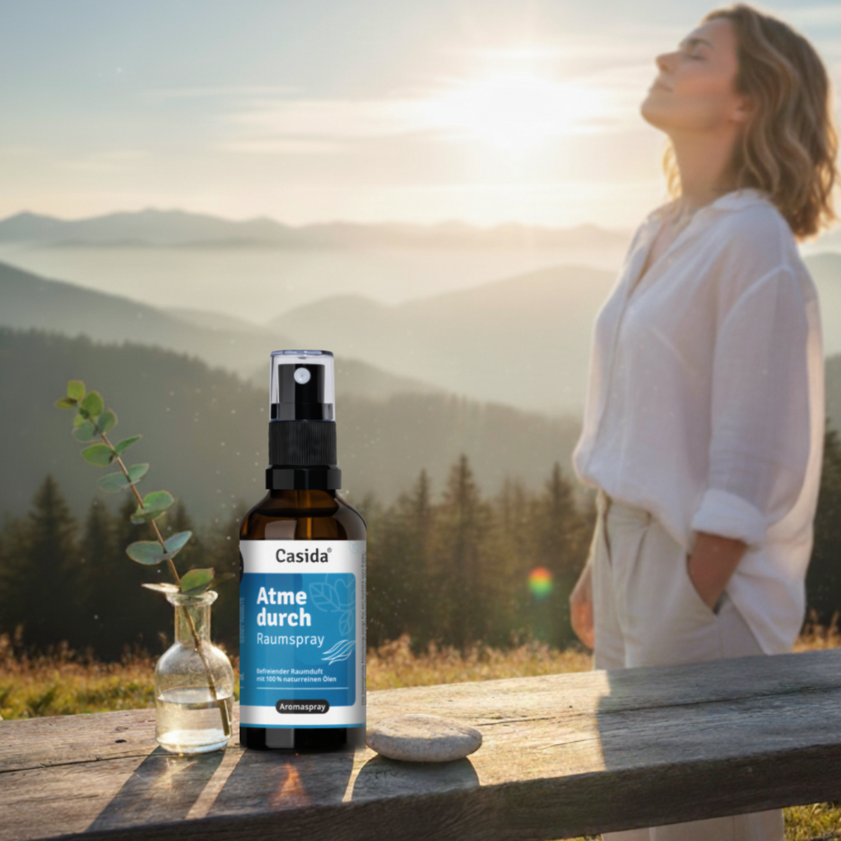 Atme durch raumspray bottle on a wooden table with a scenic mountain background and a woman in profile.