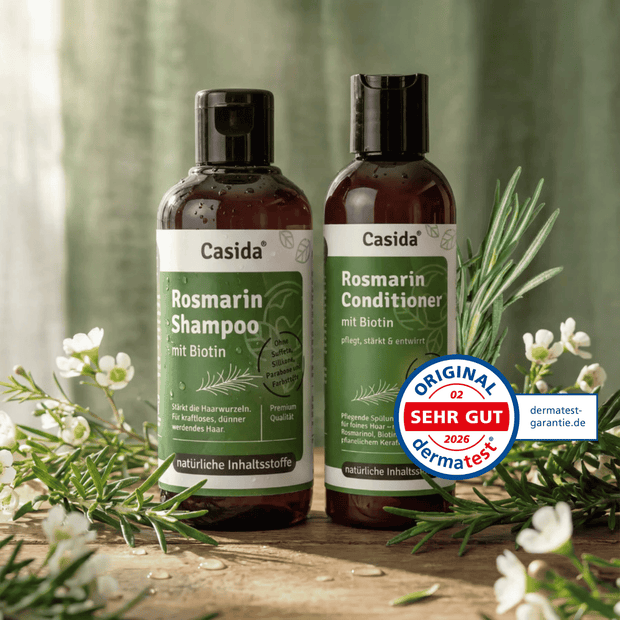 Rosmarin shampoo and conditioner set with biotin, featuring dark bottles and green labels, surrounded by rosemary and flow...