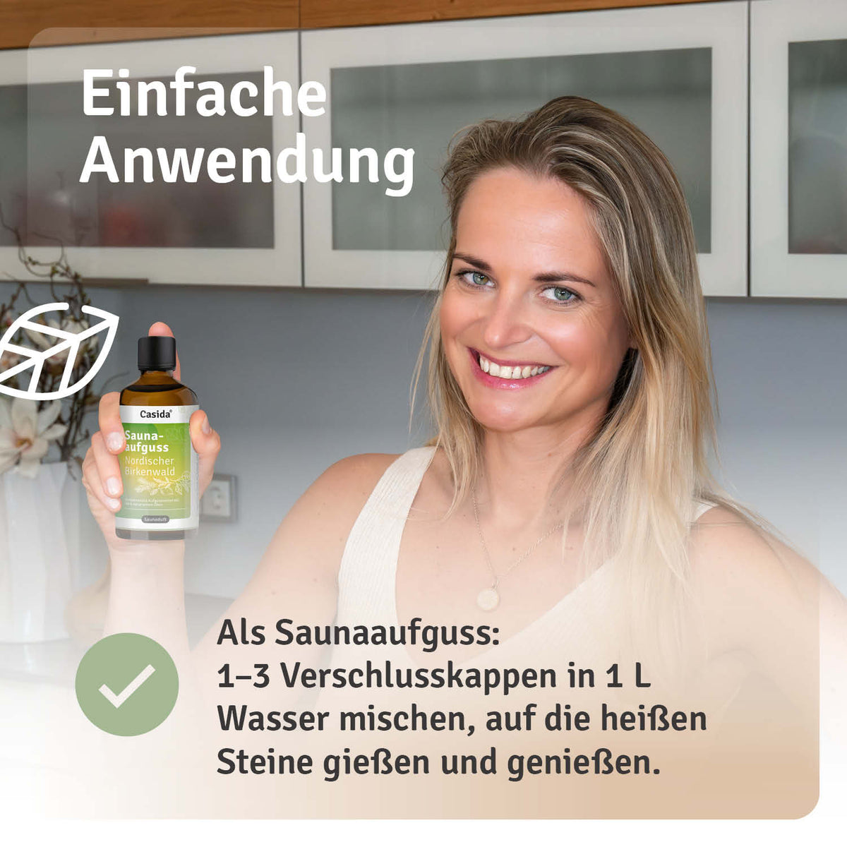 Saunaaufguss Nordischer Birkenwald oil in a bottle held by a smiling woman, with application instructions visible in the b...