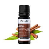 Zimtöl in a dark glass bottle with a black cap, surrounded by cinnamon sticks and green leaves.